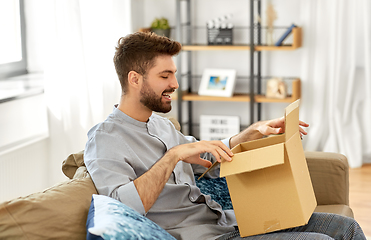 Image showing happy man opening parcel box at home