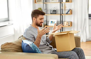 Image showing disappointed man opening parcel box at home