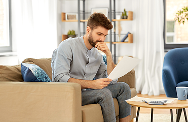 Image showing man with bills counting on calculator at home