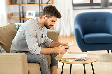 Image showing man with money and calculator filling papers