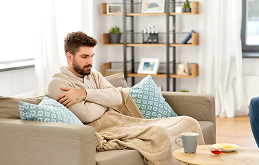 Image showing sick young man in blanket with hot tea at home