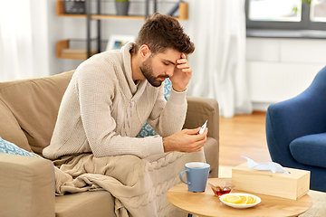 Image showing sick man measuring temperature by thermometer