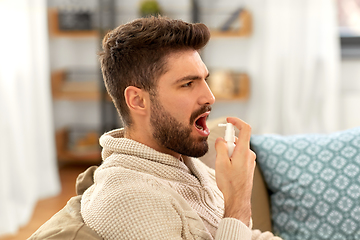 Image showing sick indian man using oral spray at home