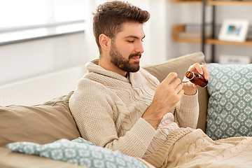 Image showing sick man pouring medication from bottle to spoon