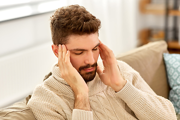 Image showing unhappy man suffering from head ache at home