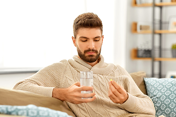 Image showing sick man with glass of water and medicine at home