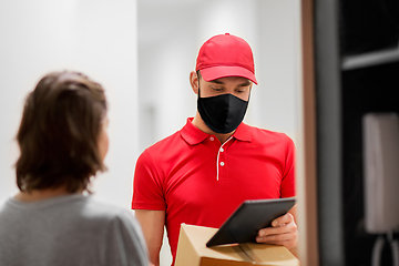 Image showing delivery man in mask with tablet pc and box