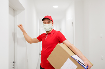 Image showing delivery man in mask with parcel knocking on door