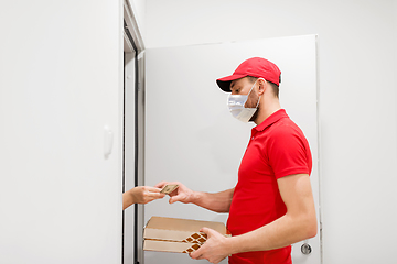 Image showing delivery man in mask taking money for pizza