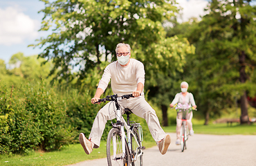 Image showing senior couple in masks riding bicycles at park