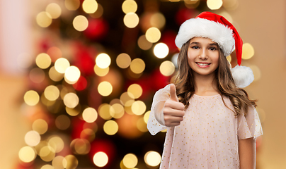 Image showing happy teenage girl in santa hat showing thumbs up