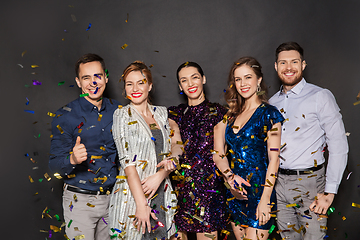 Image showing happy friends at party under confetti over black