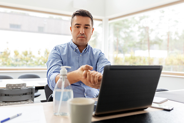 Image showing man using hand sanitizer at home office