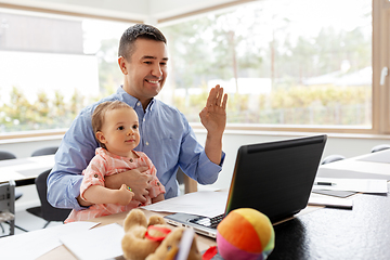 Image showing father with baby working on laptop at home office