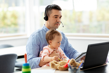 Image showing father with baby working on laptop at home office