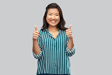 Image showing happy asian woman showing thumbs up over grey