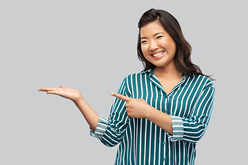 Image showing happy asian woman holding something on hand