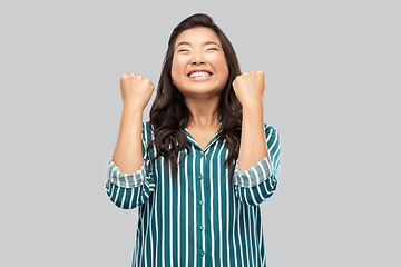 Image showing happy asian woman celebrating success over grey