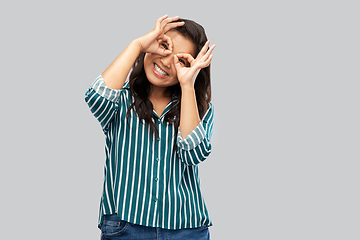 Image showing smiling asian woman looking through finger glasses