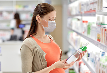 Image showing pregnant woman in mask choosing lotion at pharmacy