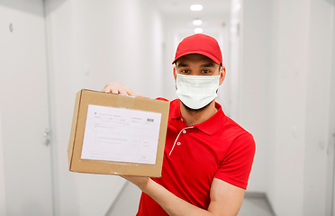 Image showing delivery man in mask with parcel box in corridor