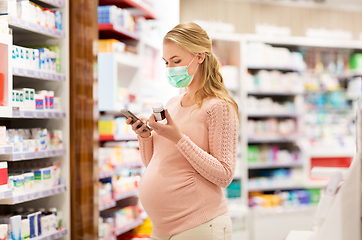 Image showing pregnant woman in mask with medicine at pharmacy