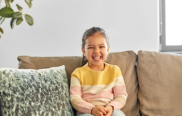 Image showing happy smiling little girl sitting on sofa at home