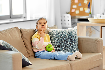 Image showing little girl with apple sitting on sofa