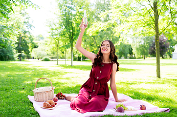 Image showing happy woman with picnic basket and drink at park