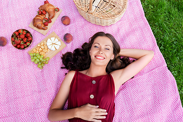 Image showing happy woman lying on picnic blanket at summer park