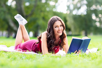 Image showing happy smiling woman reading book at summer park