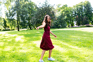 Image showing happy smiling woman walking along summer park