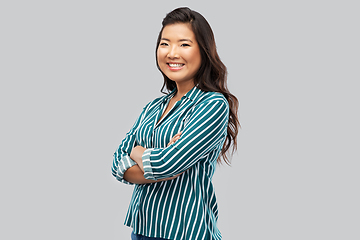 Image showing happy asian woman with crossed arms on grey