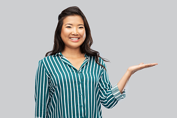 Image showing happy asian woman holding something on hand