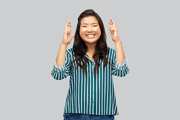 Image showing happy smiling asian woman holding fingers crossed