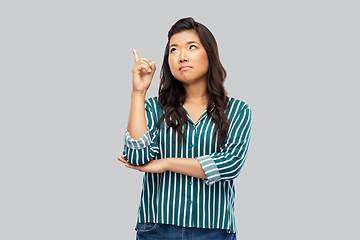 Image showing asian woman pointing finger up on grey