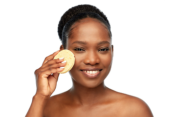 Image showing young woman cleaning face with exfoliating sponge