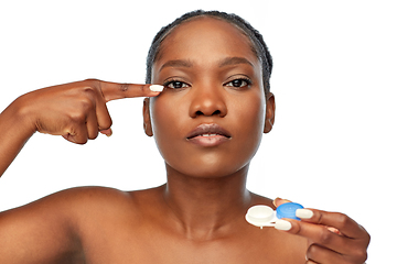 Image showing african american woman putting on contact lenses