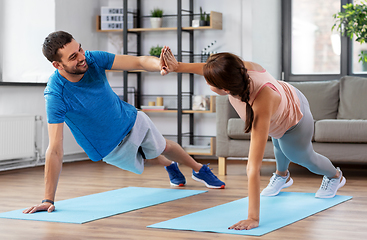 Image showing happy couple make high five in side plank at home