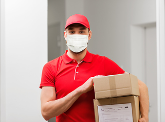 Image showing delivery man in mask with parcel box in corridor