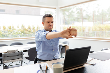 Image showing tired man with laptop stretching at home office