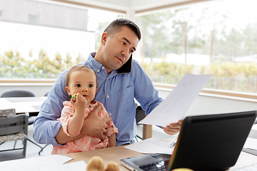 Image showing father with baby calling on phone at home office