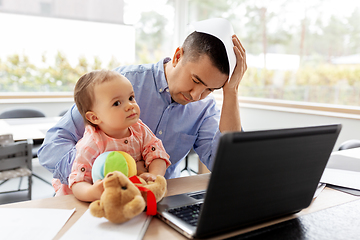 Image showing father with baby working on laptop at home office