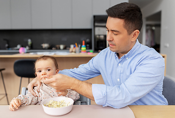 Image showing middle-aged father feeding baby daughter at home