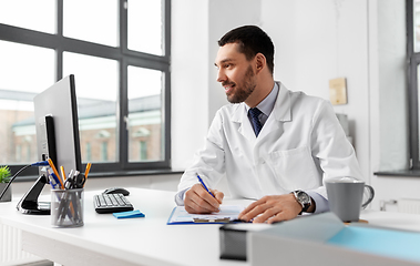 Image showing smiling male doctor with clipboard at hospital