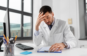 Image showing stressed male doctor with clipboard at hospital