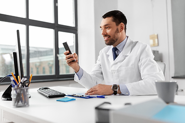 Image showing smiling male doctor with smartphone at hospital