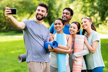 Image showing happy people with yoga mats taking selfie at park