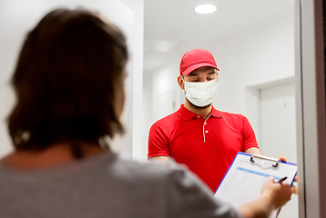 Image showing delivery man in mask and customer signing papers