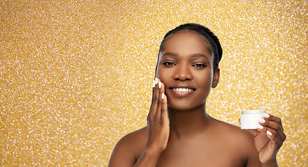 Image showing smiling african american woman with moisturizer